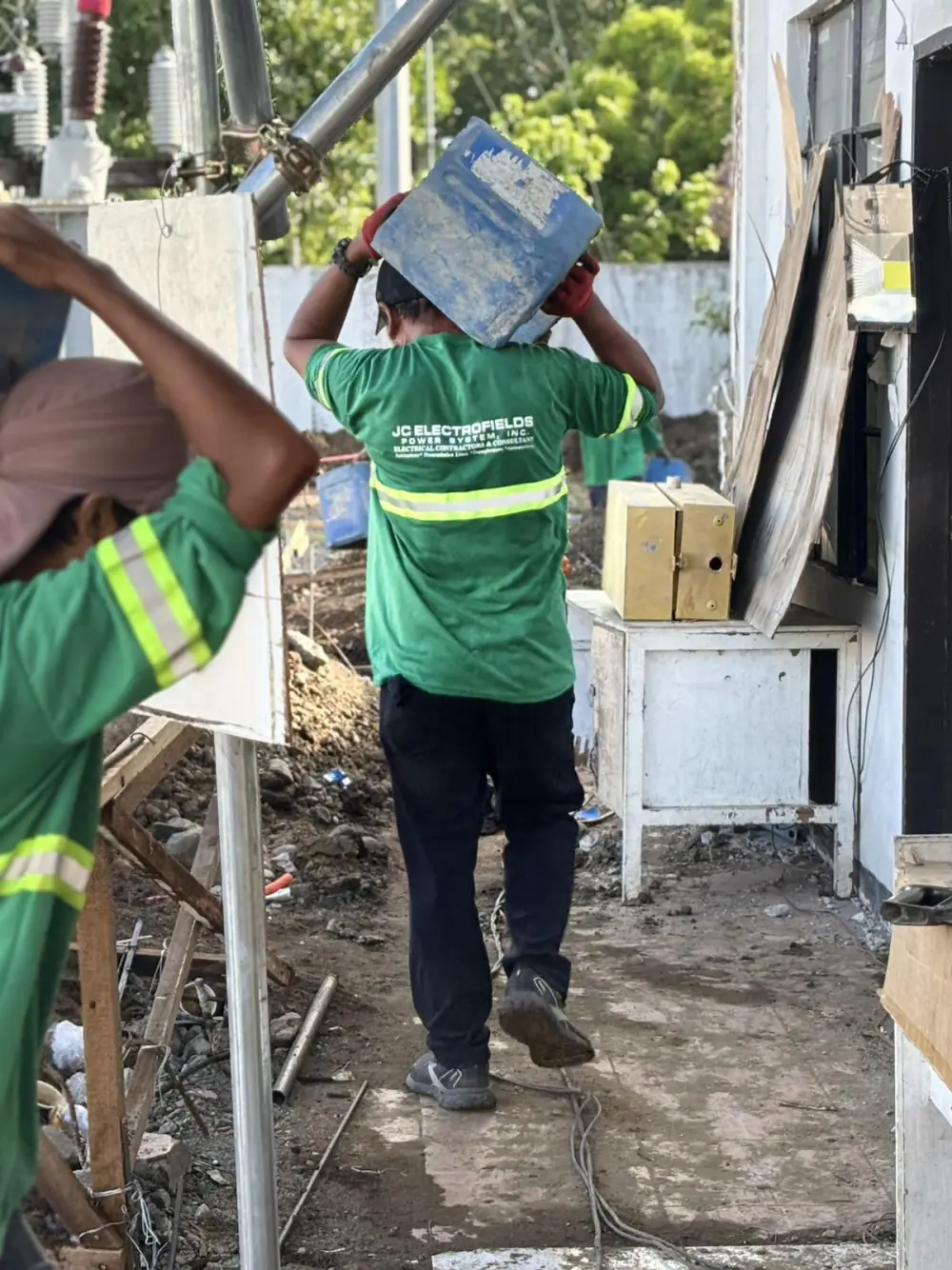 A JC Electrofields worker carrying materials on-site past substation equipment